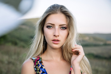 beautiful dreamy blonde girl with blue eyes in a light turquoise dress lying on the stones