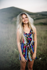 beautiful dreamy blonde girl with blue eyes in a light turquoise dress lying on the stones