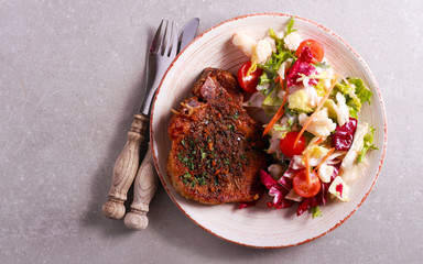 Spicy pork chop and salad on plate