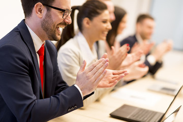 Happy smiling business team clapping hands during a meeting