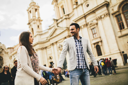 Casual young couple holding hands walking in Rome, Italy, Europe