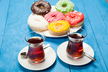 Two cups of tea and donuts on a blue wooden table