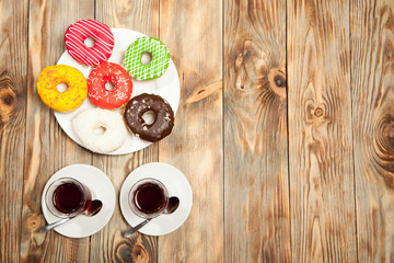 Two cups with coffee and donuts on a wooden background