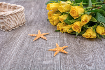 Orange starfishes and roses on a wooden background