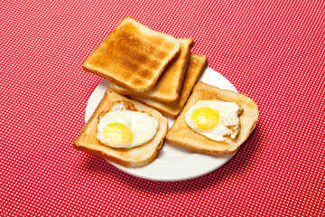 Toasts and eggs on a plate on a red table