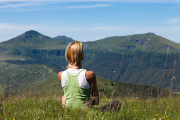 Fototapeta na wymiar femme assise de dos au soleil regardant les volcans en été