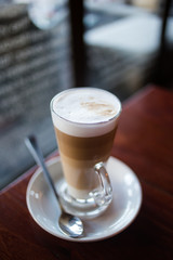 Close up image of a Caffe Latte in a coffee shop with natural window light inside a dark interior