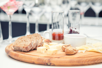Different delicious cheeses brie, blue cheese, rosette of swiss cheese Tete de Moine, cheese of thyme with nuts and dressing on wooden round board. Low key tone.