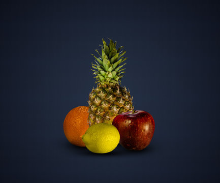 Pineapple, lemon, orange and apple isolated on dark blue background