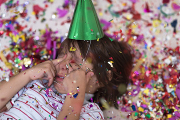 Obraz na płótnie Canvas kid blowing confetti while lying on the floor