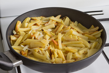 fried potatoes in a frying pan on a gas stove