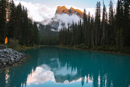 Reflection of trees and mountain peaks on turquoise lake 