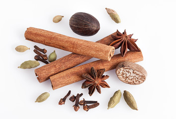 Cinnamon, anise, nutmeg, cardamom on white background.