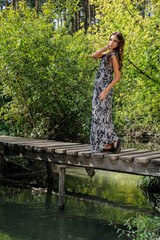 Attractive young woman stands on a wooden bridge outdoors