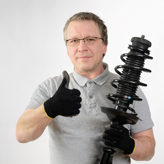 Auto Mechaniker mit Stoßdämpfer in der Hand, Federbein, Feder 