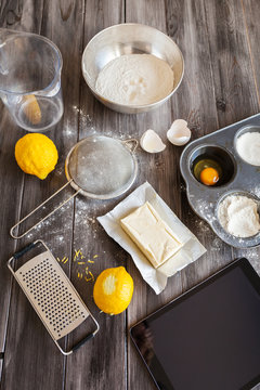 Ingredients for the dough. Eggs, flour, butter, sugar, lemon and kitchen tools on a dark wooden background. Rustic background. Flat lay. Top view. The process of making cakes for a cake Napoleon