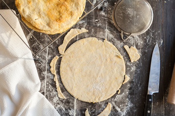 Roll up dough for Napoleon cake. Preparation process against a dark wooden table
