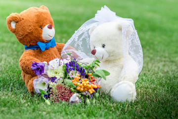 Plush bear cubs on the green grass and a beautiful bouquet