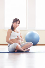 Portrait of a beautiful young pregnant woman executing exercises with fitball