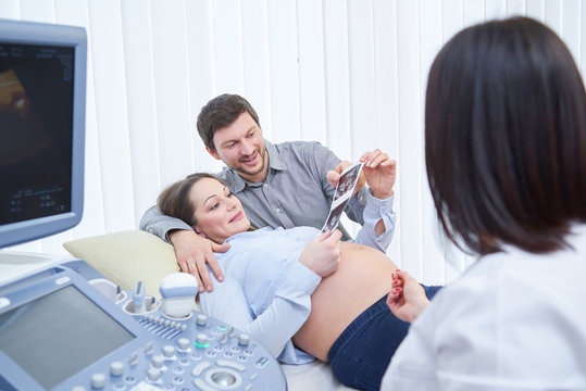 Loving Couple Attending Doctor For Pregnancy Ultra Sound Procedu