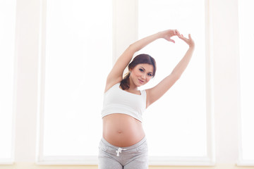 Fototapeta na wymiar Young beautiful pregnant woman standing near window at home