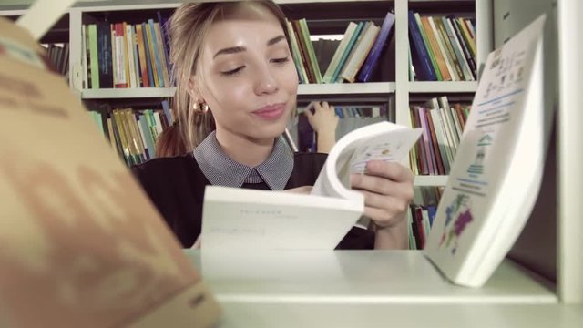 Close-up of smiling female student choosing a suitable from bookcase