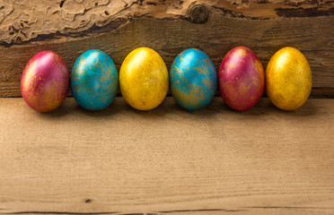 Multi-colored easter eggs on a natural wooden background. Copy space.