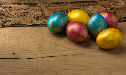 Multi-colored easter eggs on a natural wooden background. Copy space.
