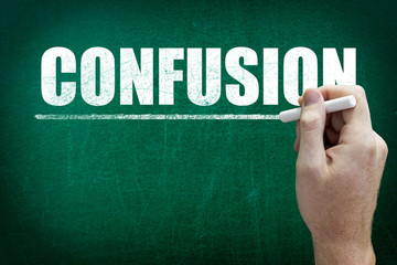 Hand writing the text CONFUSION on the blackboard