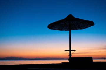 Fototapeta na wymiar silhouette of umbrella on the beach in twilight