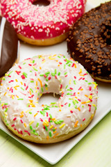 Cup of coffee and tasty donuts with icing and chocolate on green wooden background, copy space