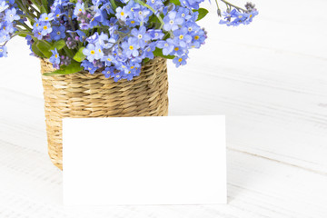 blue flowers bouquet with blank card on white wooden background