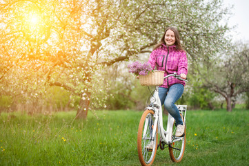 Obraz premium Female cyclist riding a vintage white bicycle in spring garden