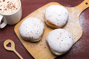 Classic donuts with powdered sugar, on wooden background