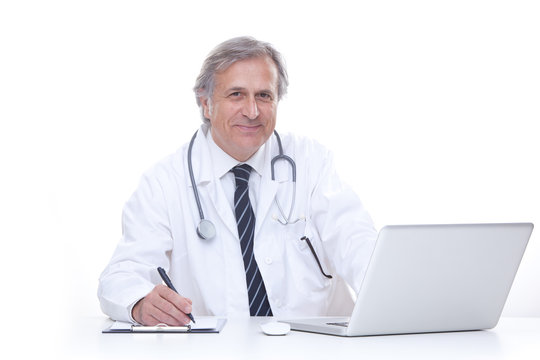 happy senior doctor with stethoscope working with laptop isolated on white