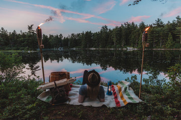 Woman relaxing beside lake, watching sunset, rear view
