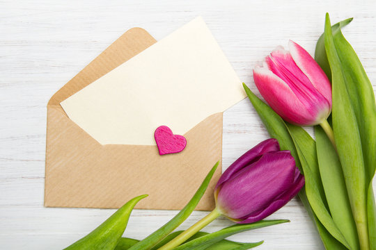 Tulip and envelope on white wooden background, copy space