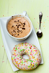 Cup of coffee and tasty donuts with icing and chocolate on green wooden background, copy space