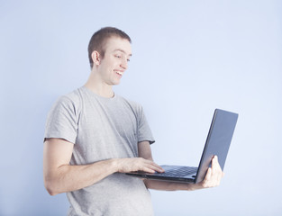 Young man with black laptop on blue background
