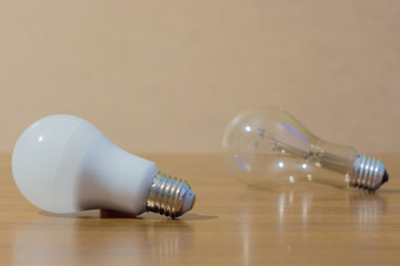 Two light bulbs. LED white and ordinary lamp on wooden background