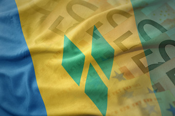 colorful waving national flag of saint vincent and the grenadines on a euro money banknotes...
