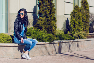 
Brunette woman with blue shirt and jeans smoking in city