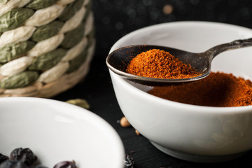 Ceramic bowl with ground paprika and metal spoon above it