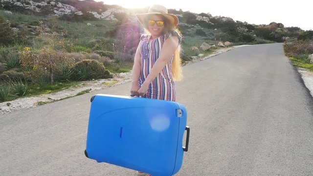 Happy Woman walking with suitcase on road