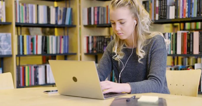 Dedicated female student working on laptop in the library