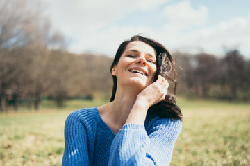 Fun attractive happy young woman being playful and carefree with beautiful hair on sunny day. Lifestyle concept. Happy female portrait on summer or spring day outside in park. Enjoy fun and sunny day.