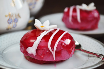 Souffle cakes with raspberry fondant icing decorated white sugar flowers. Soft focus.