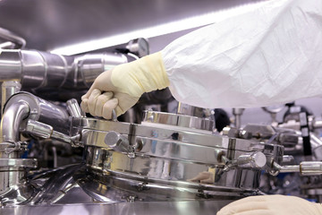 A man opens a chemical reactor. Rector of the pharmaceutical industry. The man closes the reactor. Production of granulate, suspension for tablets.