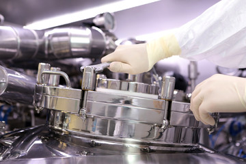 A man opens a chemical reactor. Rector of the pharmaceutical industry. The man closes the reactor....