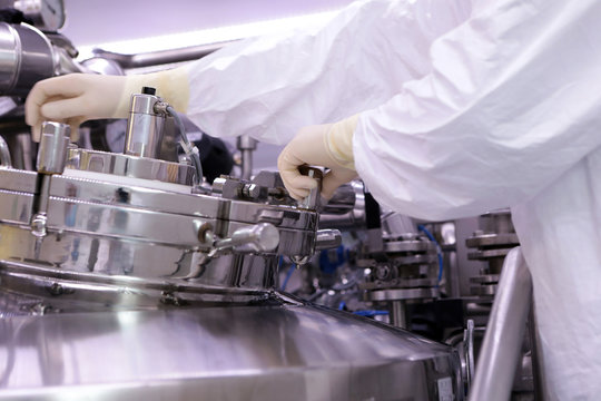 A man opens a chemical reactor. Rector of the pharmaceutical industry. The man closes the reactor. Production of granulate, suspension for tablets.